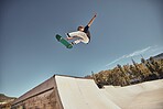 Sports, skateboarding and skater in air at park doing tricks, skating and having fun in urban town. Fitness, freedom and man do action skills, jumping and cool movement for sport, hobby and exercise