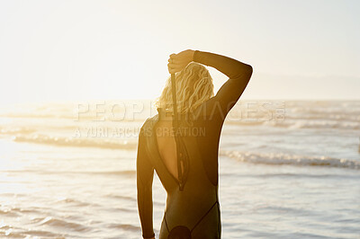 Buy stock photo Zip, swimsuit and woman surfer ready to surf at the beach, sea and ocean waves in sunset or sunrise on holiday. Back view, surfing and person relax on vacation enjoying sports, exercise or workout 