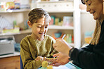 Art, creative and teacher and student painting hands for learning, education and project. Happy, artist and a woman applying paint to the hand of a student for creativity, class work and hobby