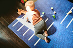 Above, baby and boy with toys on floor for building, learning and fun in his home. Top view, toddler and playful, curious and child with blocks in nursery for education, development or sensory skills