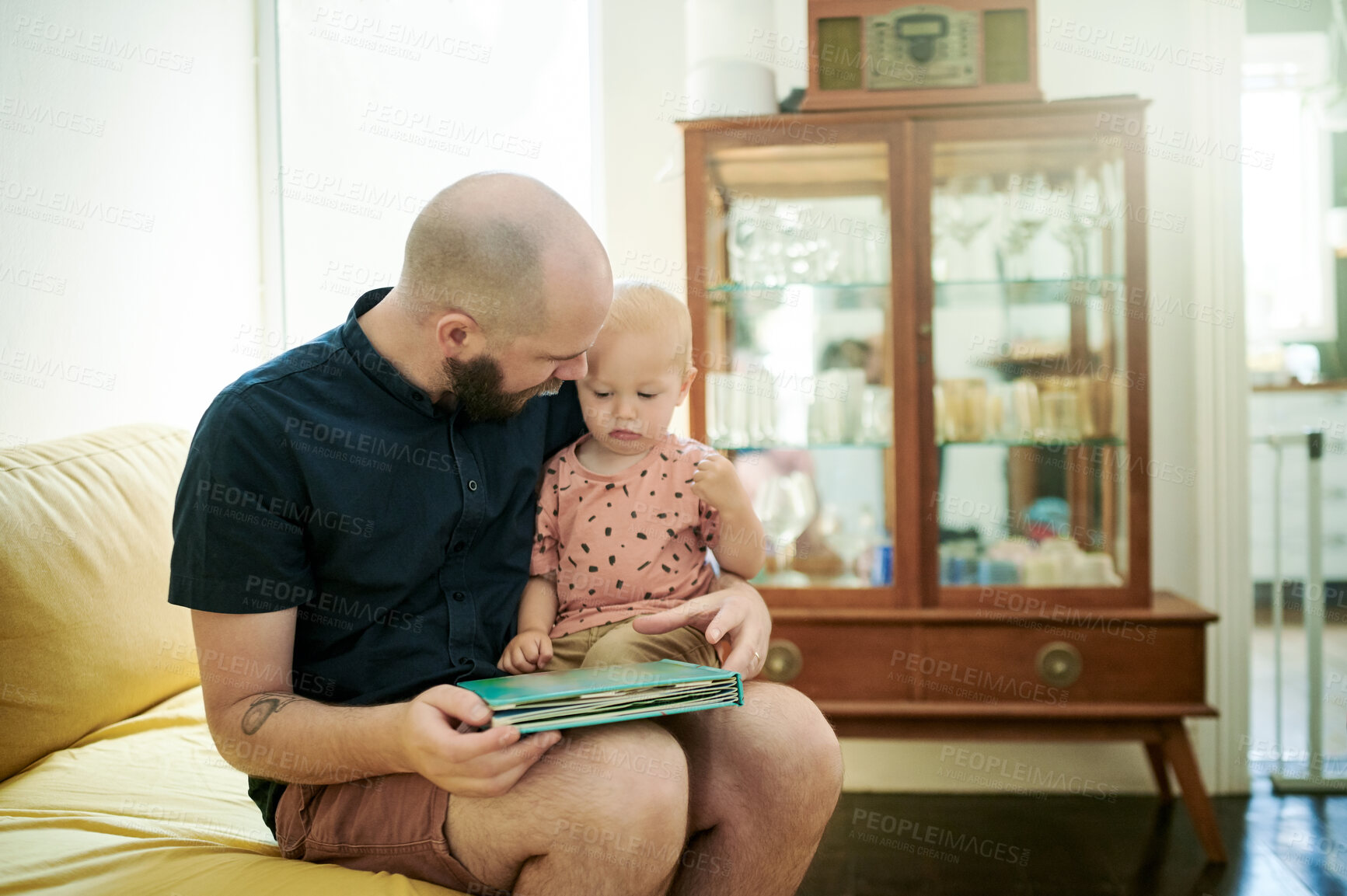 Buy stock photo Dad, baby and reading book in a family home living room for fun. Man or dad with toddler kid on couch for quality time, love and care or learning, talking and together for story or development