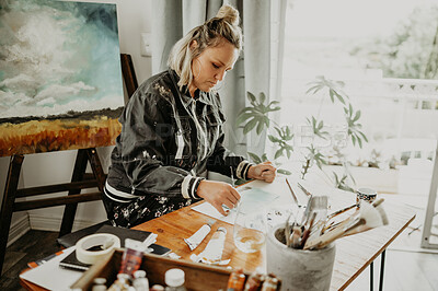 Buy stock photo Creative, drawing art and woman in studio at desk for painting hobby, illustration and artwork creation. Home workshop, artist and female person with paintbrush, paper and canvas for creativity