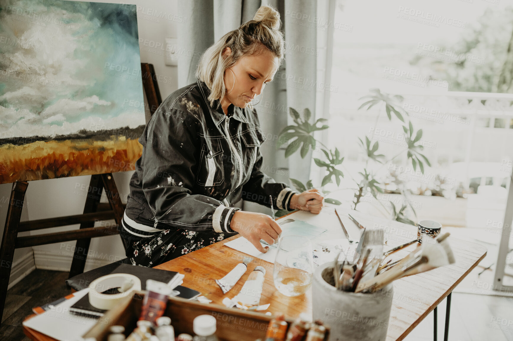 Buy stock photo Creative, drawing art and woman in studio at desk for painting hobby, illustration and artwork creation. Home workshop, artist and female person with paintbrush, paper and canvas for creativity