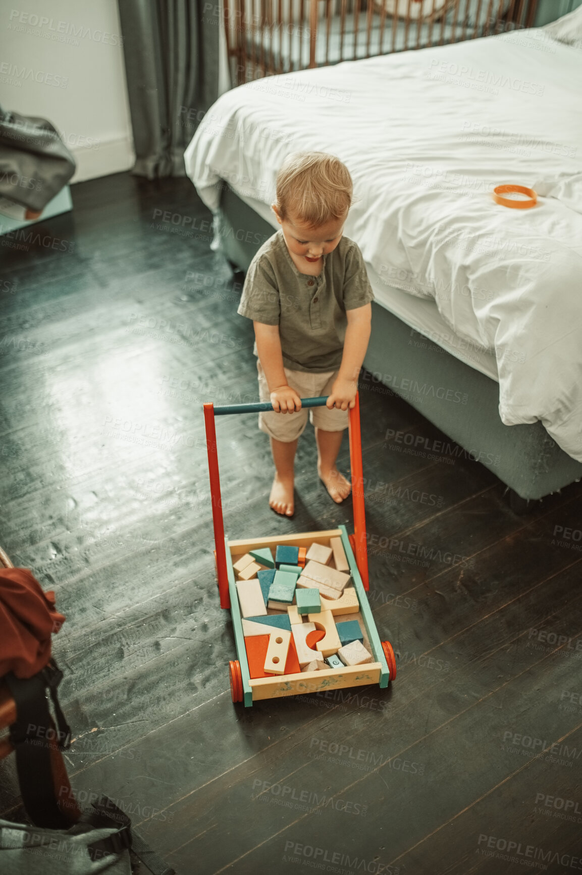 Buy stock photo Bedroom, toys and toddler kid playing in his nursery for child development and fun at home. Playful, cute and little boy infant or baby walking with wood barrow in his playroom in the family house.