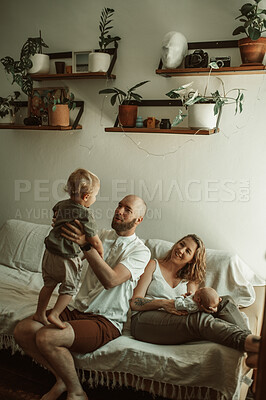 Buy stock photo Family, playing and parents with baby and toddler on a sofa with smile, care and relax in their home together. Newborn, love and mother and father with children in a living room bonding in a house