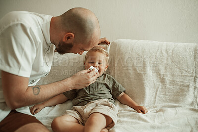 Buy stock photo Dad, child and wipe nose of sick kid on sofa in home living room, happy and smile for care. Father, boy and toddler with tissue for flu, allergies or covid, virus or disease, illness or cold in house