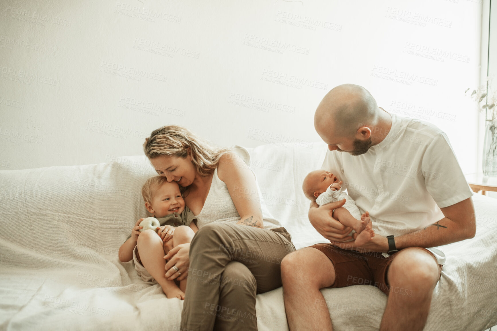 Buy stock photo Love, bonding and parents with their children on sofa in the living room of their house with care and happiness. Playful, embracing and young mother and father relaxing with newborn baby and toddler.