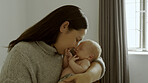 Kiss, love and mother bonding with her newborn in the modern nursing room at family home. Smile, care and young mom holding her infant, baby or child with happiness in the bedroom of house in Canada.