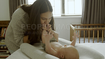 Buy stock photo Parent, newborn and mother kiss baby as love, care or bonding in a home as fun affection together. Happiness, woman and mom relax in bedroom playing with infant kid toes or feet as family in house