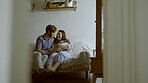 Mother, father and baby on a sofa in their home living room together for love, care or bonding. Security, smile and relax with happy young parents holding their cute newborn infant chid in a house