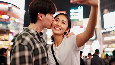 Buy stock photo City, night and selfie with couple on street together in Japan for bonding, love or tourism. Kissing, photograph and smile of Japanese woman with man in urban town for holiday, travel or vacation