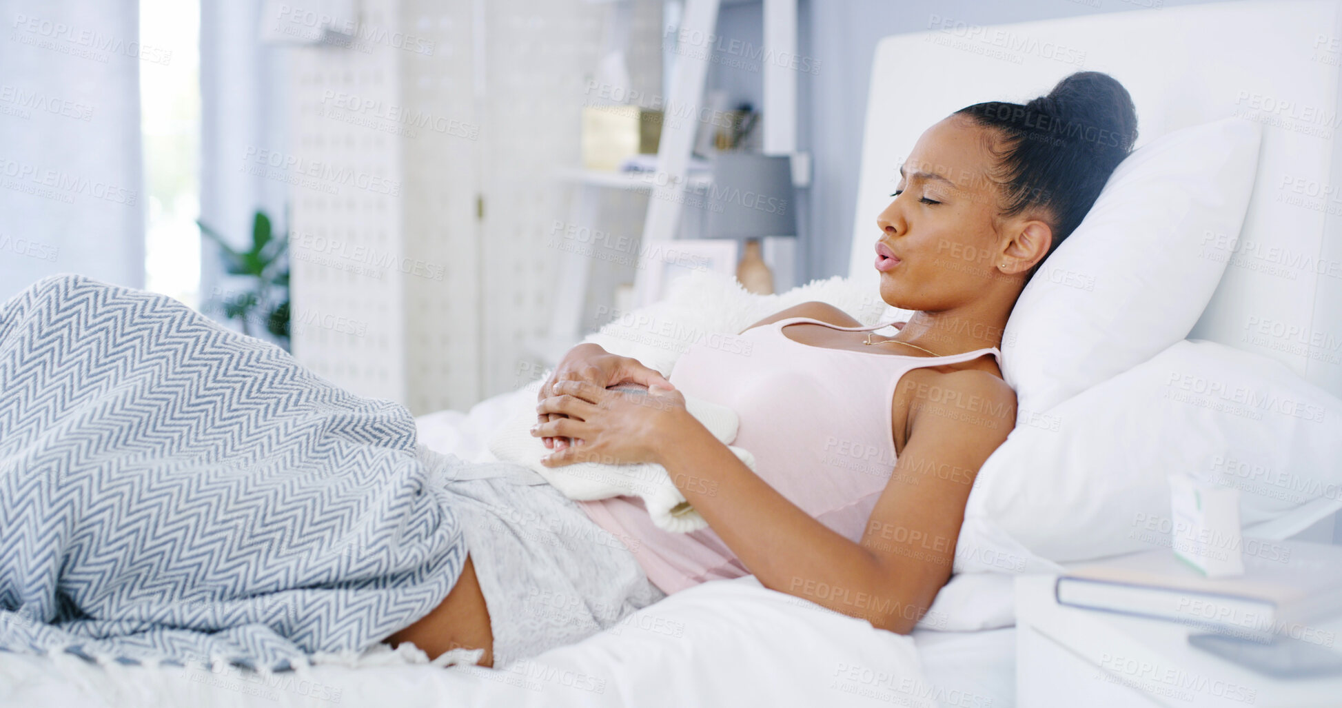 Buy stock photo Hot water bottle, woman and stomach pain in home on bed with period cramps, menstruation or inflammation. Resting, discomfort or girl with abdominal ache in bedroom for medical emergency, pms or sick