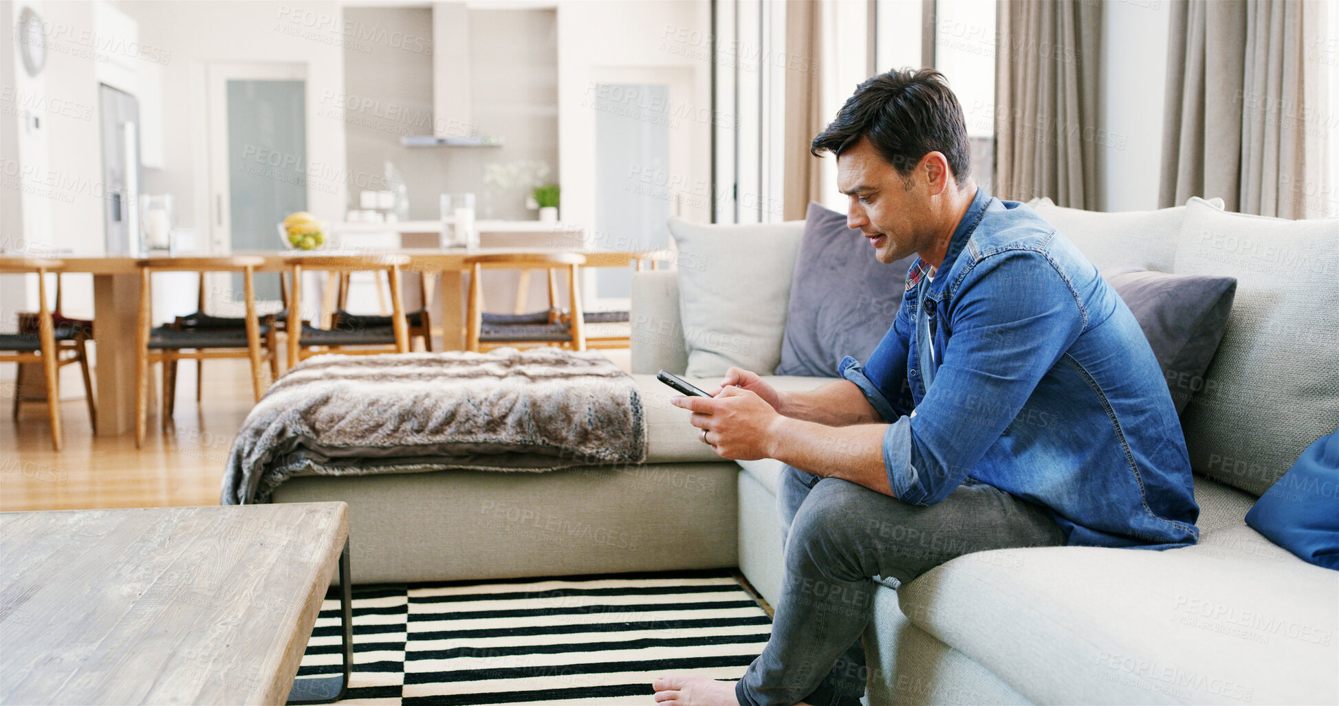 Buy stock photo Home, relax and man with phone on sofa online for social media, reading website and internet search. Living room, house and person on smartphone on weekend for chilling, communication and contact