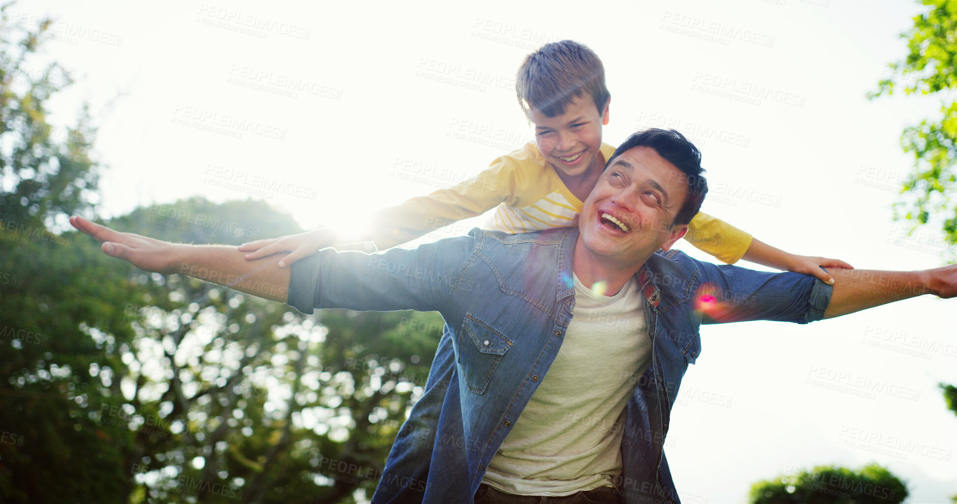 Buy stock photo Father, piggyback and outdoor flying with son, fantasy adventure and holiday park for bonding. Happy family, lens flare and nature for support with airplane games, freedom and together on vacation