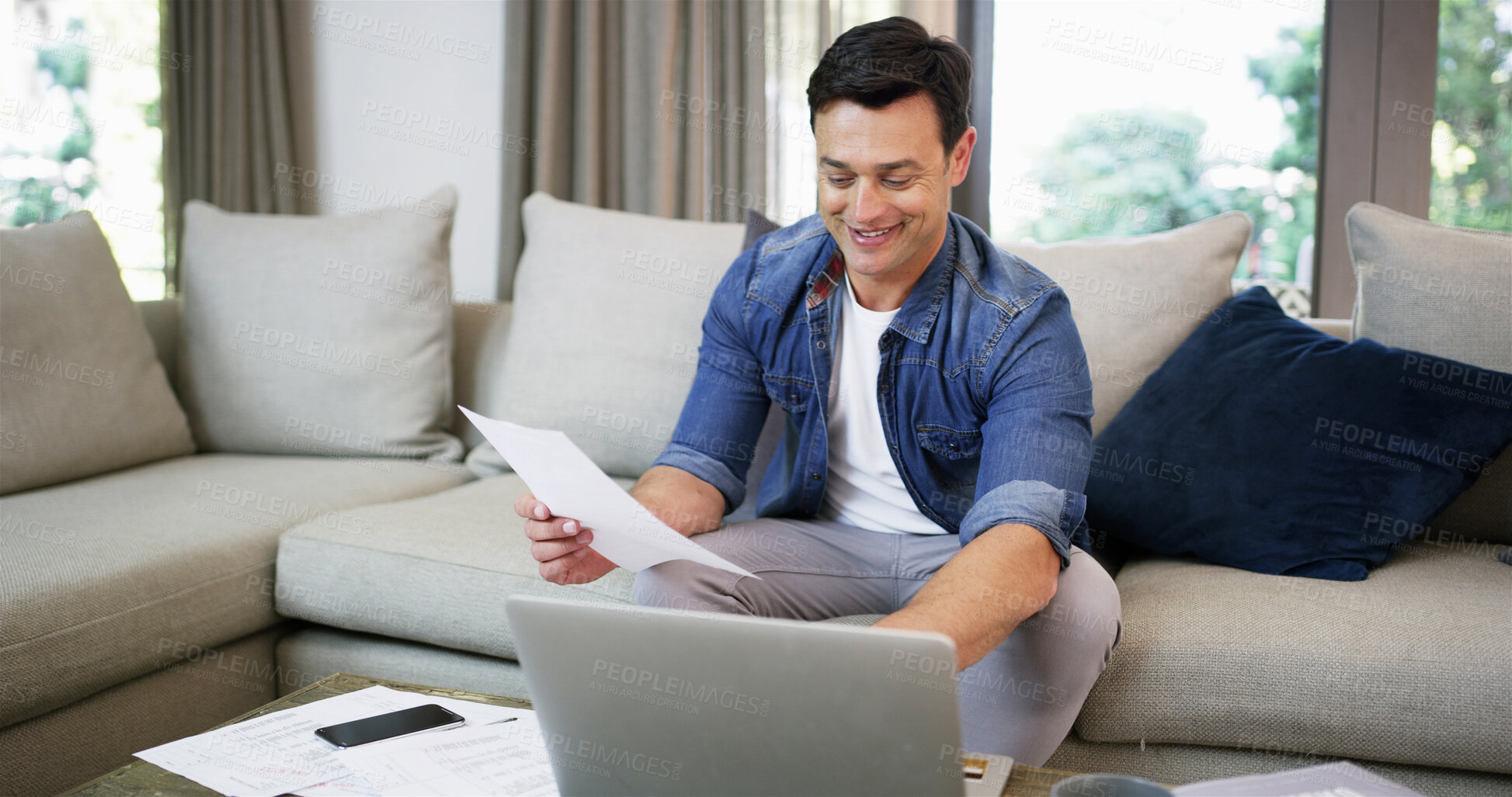Buy stock photo Sofa, man and laptop with documents for finance, track expenses and success for budget goal at home. House, male person and happy with paperwork for payment review, digital savings and mortgage bills