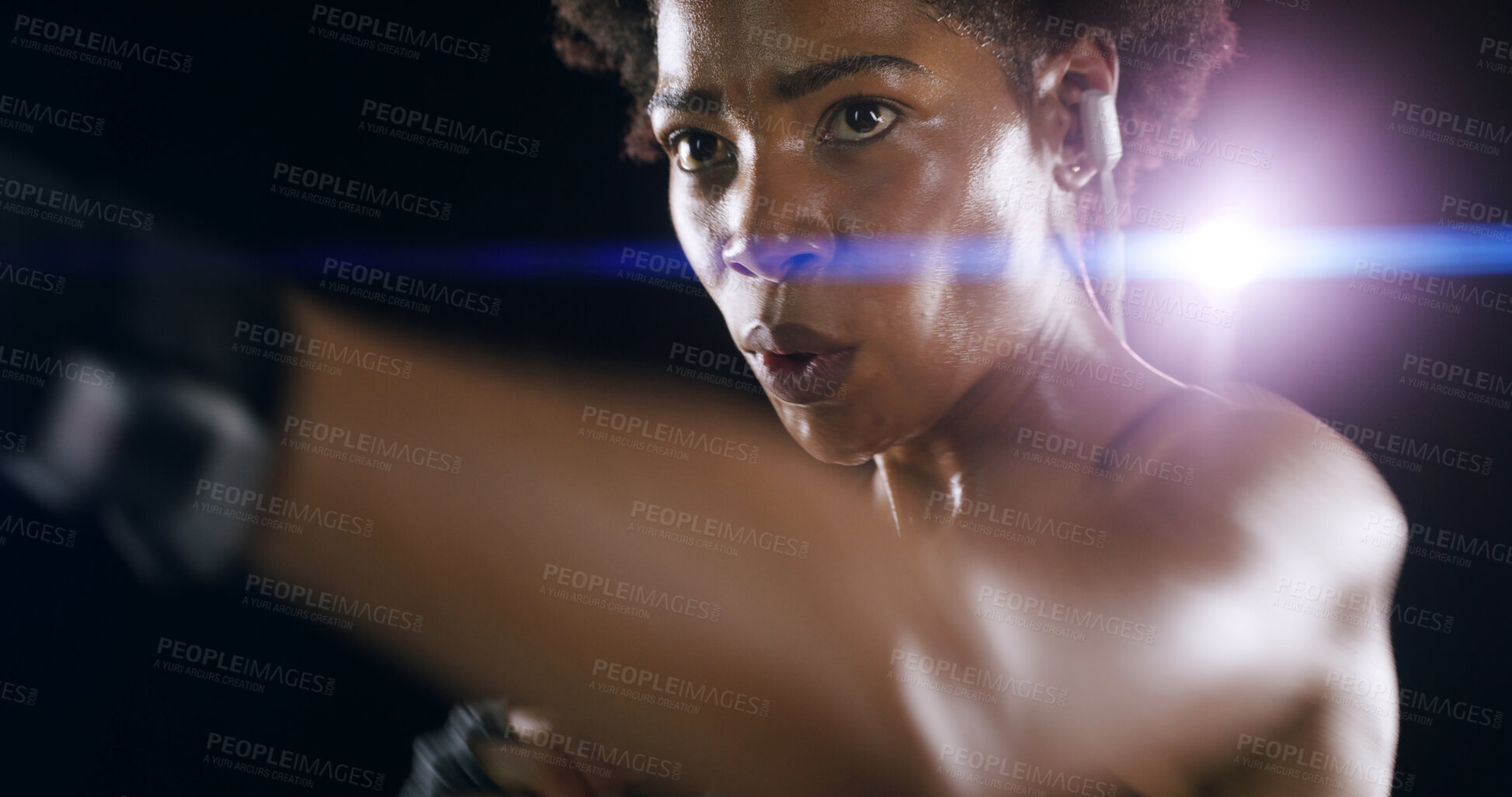 Buy stock photo African woman, boxing and earphones for training, music and lens flare for martial arts by black background. Girl, person and punch with audio streaming, exercise and workout for fight competition