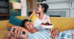 Happy, eating and couple with fruit on sofa for bonding, love and connection together in home. Relax, marriage and people with healthy snack with watching movie, film or show in living room at house.