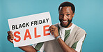 Man, portrait and paper in studio for discount, fashion sale and happy for black Friday deal. African promotor, smile and poster sign on blue background for advertising, clothing promotion and offer