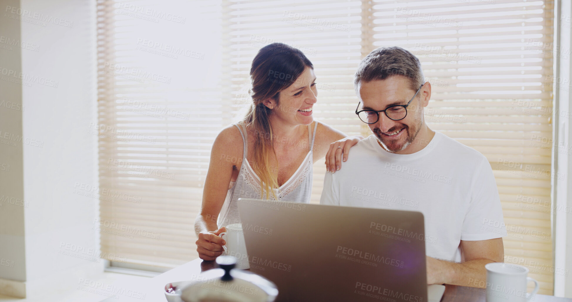 Buy stock photo Couple, smile and laptop in kitchen, breakfast and relax with coffee, streaming or social network in home. Mature man, woman and happy with computer, tea and watch video with subscription in house