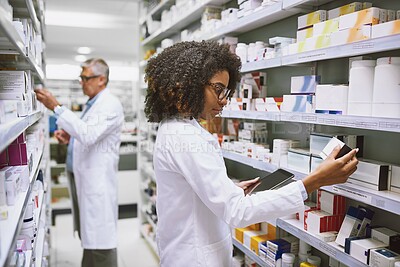 Buy stock photo Shot of two focused pharmacist walking around and doing stock inside of a pharmacy