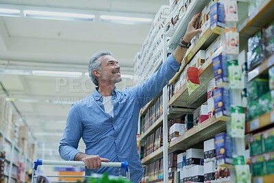 Buy stock photo Happy, shopping and man in supermarket with shelf for food, grocery and products at convenience store. Retail, consumer and person with trolley in aisle for choice, options and discount purchase