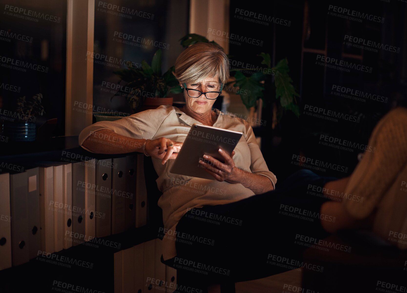 Buy stock photo Online, tablet and mature woman at desk with relax for notification, reading proposal or review. Business, night and happy person with glasses for information, email or news article in home office