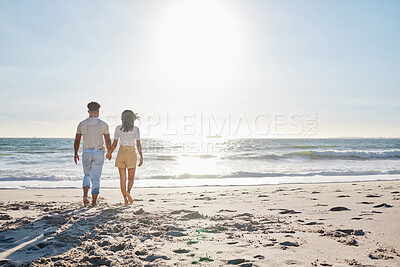 Buy stock photo Back, couple and holding hands with walking by beach for travel adventure, honeymoon vacation and fresh air. Sky space, people and bonding at seaside for anniversary date, holiday break or commitment