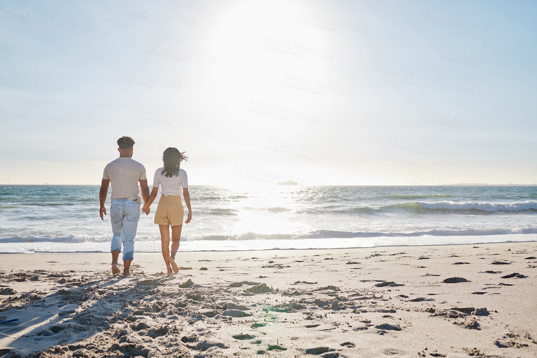 Buy stock photo Back, couple and holding hands with walking by beach for travel adventure, honeymoon vacation and fresh air. Sky space, people and bonding at seaside for anniversary date, holiday break or commitment