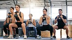 Diverse group of active young people doing kettlebell squat exercises while training together in a gym. Focused athletes challenging themselves by holding heavy weights to build muscle and endurance during a workout in a fitness class