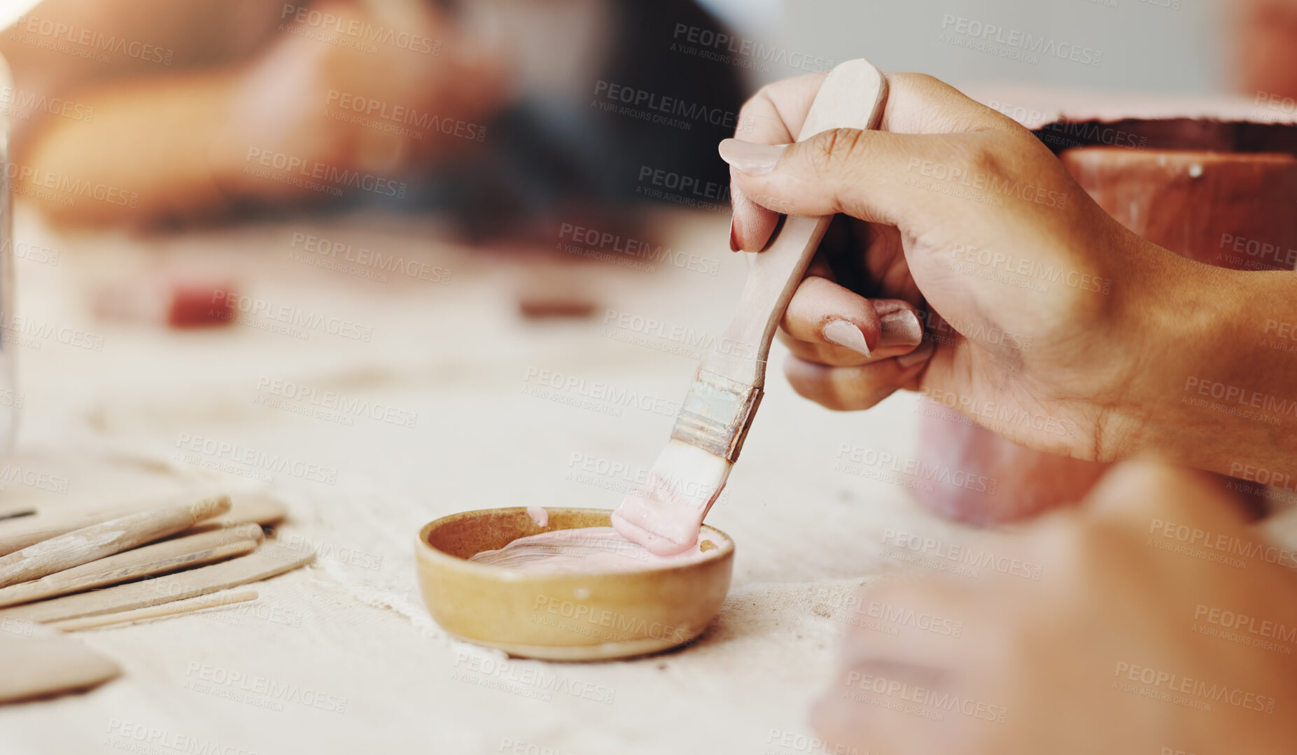 Buy stock photo Hands, brush and pottery in clay studio, workshop and art process for handmade ceramic design. Craft, hobby and artist with painting, artwork and talent in creative class for sculpture learning