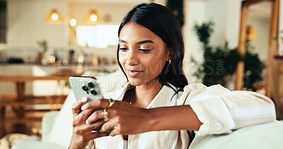 Buy stock photo Relax, smartphone and woman typing in home on app, reading news or post comment on online forum. Living room, mobile and happy Indian girl on social media, notification and download game on internet
