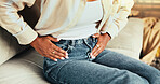 Hands, stomach ache and pain on sofa in home with digestion, virus or gastro in living room. Person, sore and touch abdomen with bloating, constipation or menstruation on couch in lounge at apartment