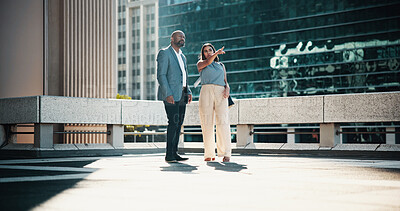 Buy stock photo Collaboration, pointing and talking with business people in city for planning or vision together. Conversation, future or meeting with man and woman employee on rooftop of building for teamwork