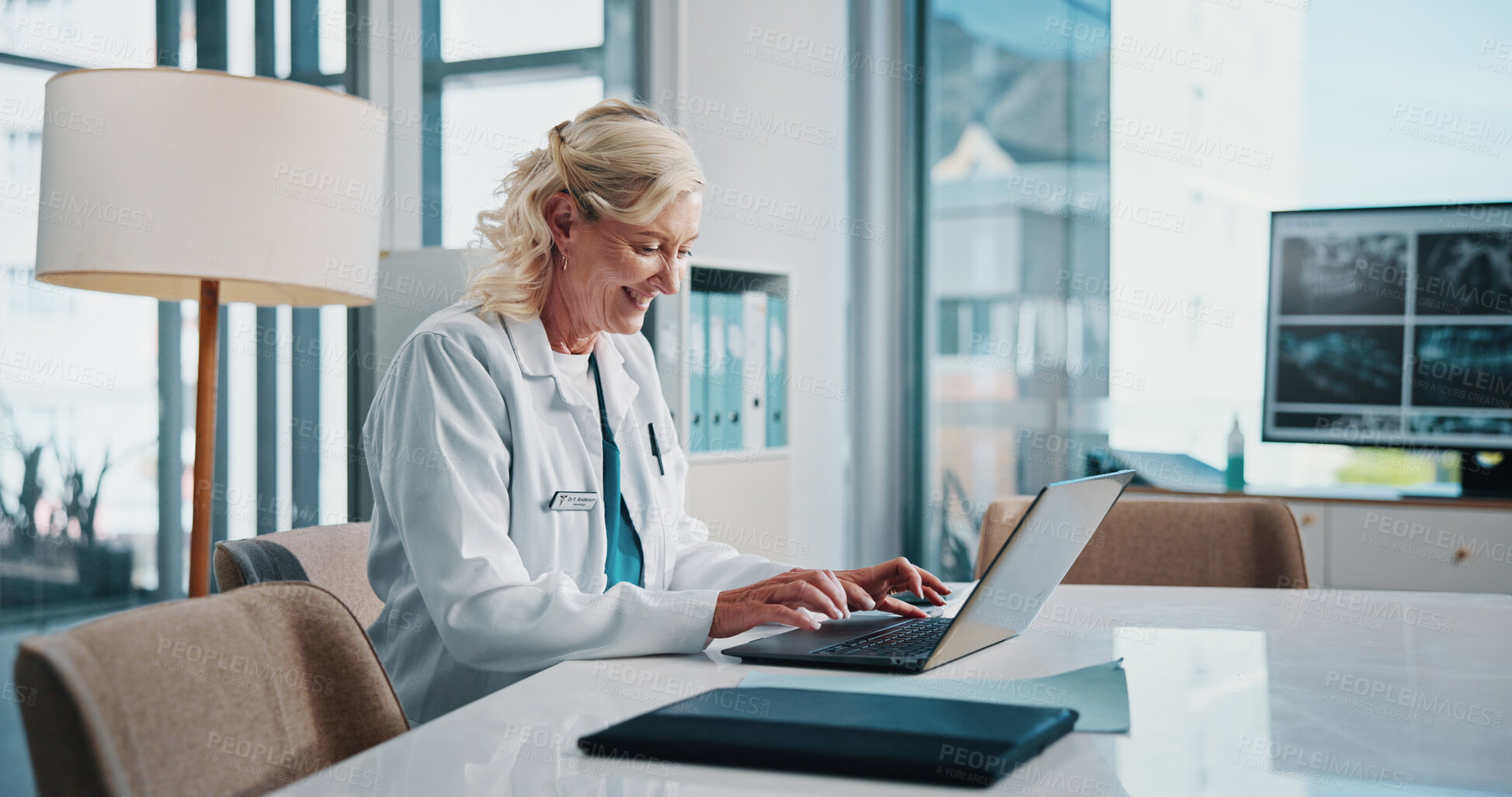 Buy stock photo Doctor, healthcare and laptop with happy woman at desk in office of hospital for diagnosis, planning or research. Computer, medical and smile with mature medicine professional typing in clinic