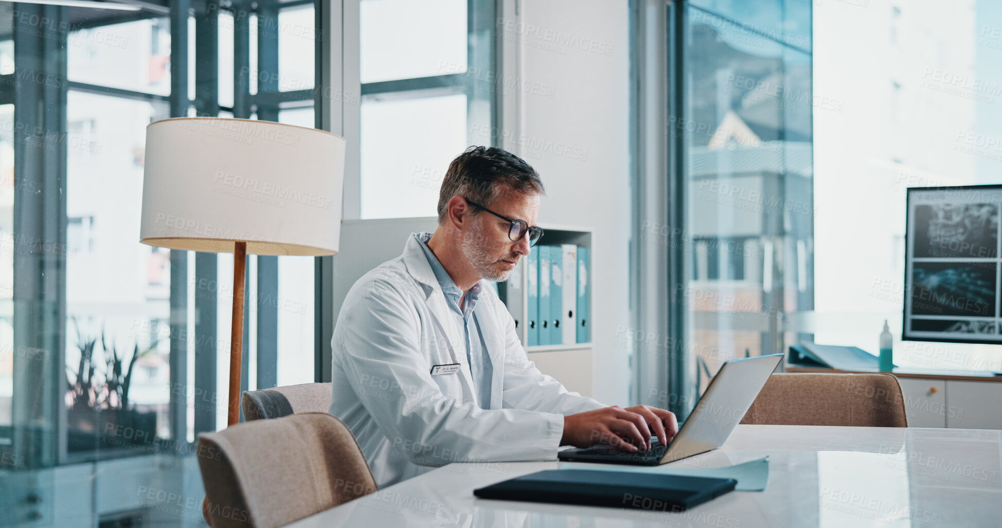 Buy stock photo Doctor, medicine and laptop with man in office of hospital for diagnosis, planning or research. Computer, medical and typing with mature healthcare professional at desk in clinic to update records