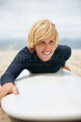 Buy stock photo Cropped shot of a female surfer lying on her surfboard