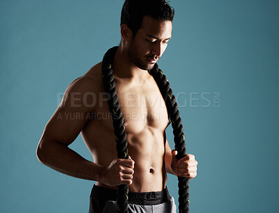 Buy stock photo Body, fitness and rope with man in studio for exercise, training or workout routine. Equipment, health and muscular with shirtless model on blue background for challenge, performance or power