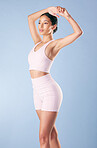Mixed race fitness woman stretching in studio against a blue background. Beautiful young hispanic female athlete warming up for exercising or working out. Dedicated to a fit and healthy lifestyle