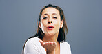 Woman, portrait and blowing with kiss for romance, affection or love on a gray studio background. Female person, face or model with hand, lips or romantic gesture for distant compassion on space