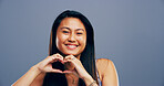 Hands in heart, studio and portrait of Asian woman with gesture for support, peace and care. Happy, confident and person with emoji, sign and hope for thank you, charity and love on blue background