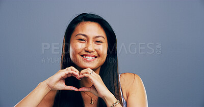 Buy stock photo Hands in heart, studio and portrait of Asian woman with gesture for support, peace and care. Happy, confident and person with emoji, sign and hope for thank you, charity and love on blue background