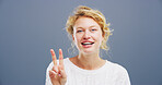 Woman, portrait and hand with peace sign in studio, icon or symbol for expression on blue background. Happy, female person and face with V gesture, emoji or show fingers for confidence by space