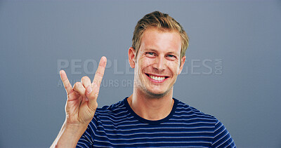 Buy stock photo Devil horn, hand and smile with man in studio for metal music, identity and space. Rocker sign, edgy and attitude with portrait of happy male person on background for cool, emoji and expression