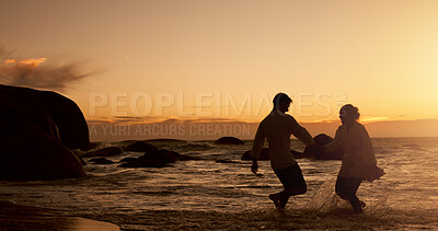 Buy stock photo Playful, couple and water at sunset on beach, vacation holiday and bonding together for anniversary. Ocean, man and woman with holding hands for love, travel adventure and connection in relationship