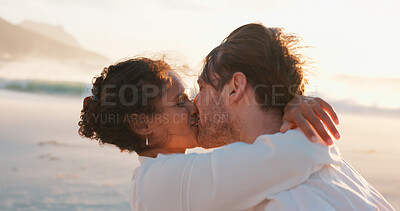 Buy stock photo Kiss, hug and couple at beach for love, care and interracial relationship together. Seashore, happy man and woman embrace outdoor for summer holiday, travel or romantic date for support at sunset