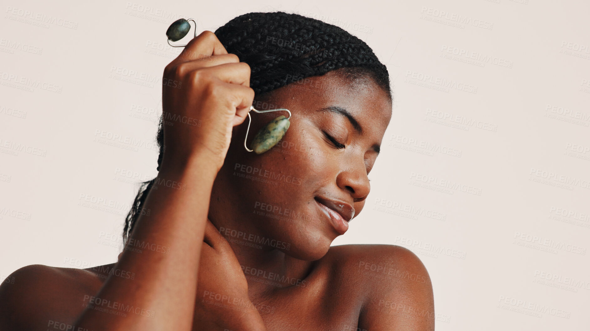 Buy stock photo Facial roller, beauty and black woman in studio with natural, health and skincare routine. Wellness, massage and African female person with jade stone tool for lymphatic drainage by white background.