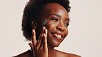 Smile, black woman and lotion on face in studio for facial hydration, treatment and sunscreen protection. Female person, apply cream and spf cosmetics for dermatology, anti aging and white background