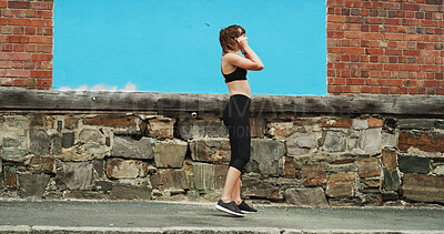 Buy stock photo Woman, city and runner with earphones by wall, space and streaming with sound, subscription and exercise. Girl, audio tech and listening to music with fitness, training and workout on road in Greece