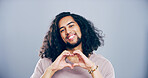Happy man, portrait and heart hands with love shape, gesture or romance on grey background space in studio. Student person, smile and emoji or sign, symbol and kindness for valentines day date mockup