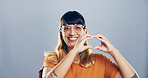 Happy woman, portrait and heart hands with glasses for love, care or romance on a gray studio background. Face, female person or romantic gesture with smile, icon or emoji for support on mockup space